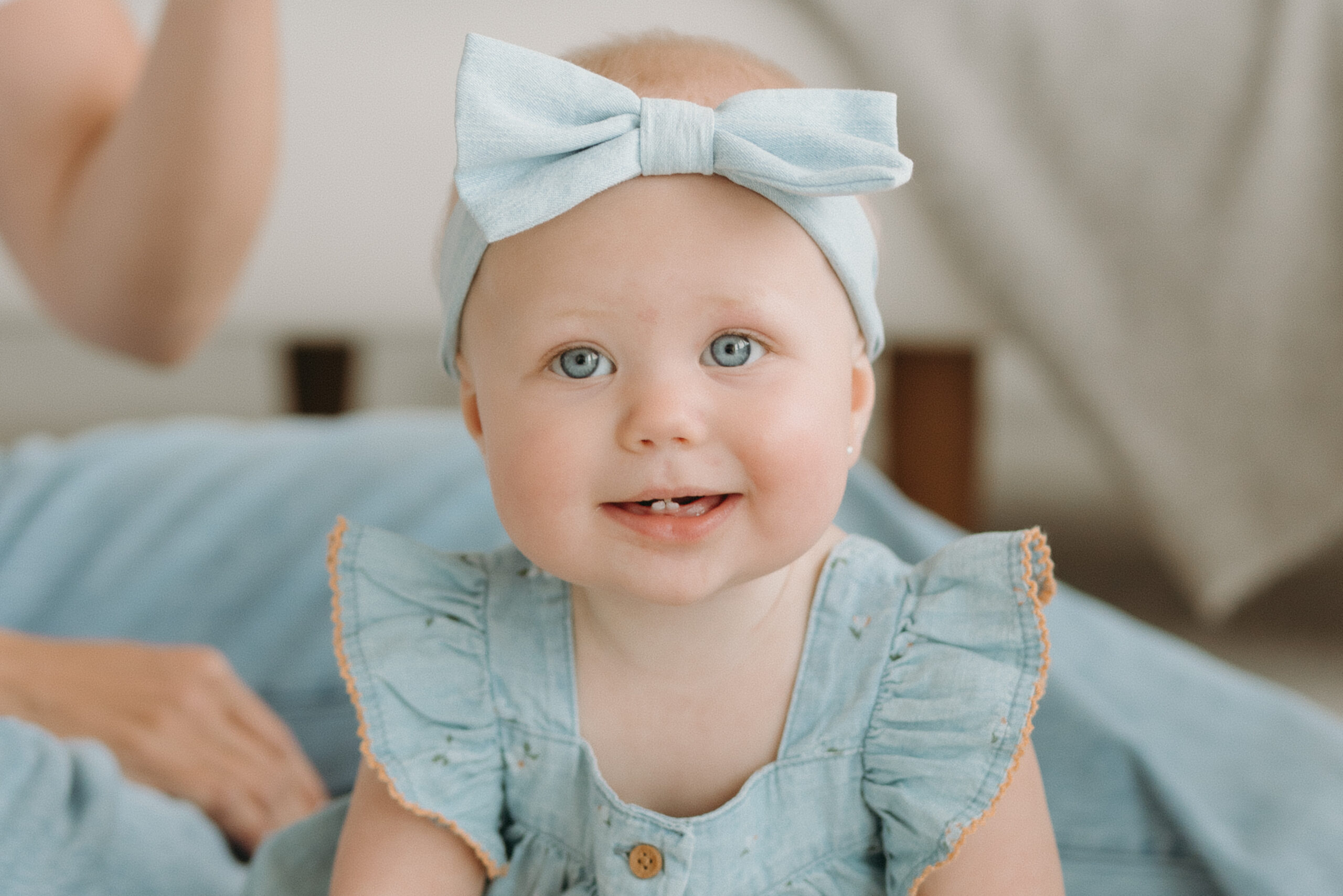 Smiling baby girl wearing a blue bow during a motherhood session at The Nook Studio in Burlington Ontario