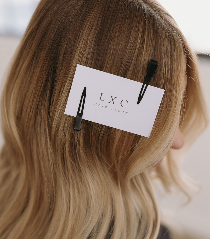 LXC Hair Salon branding card clipped in blonde hair