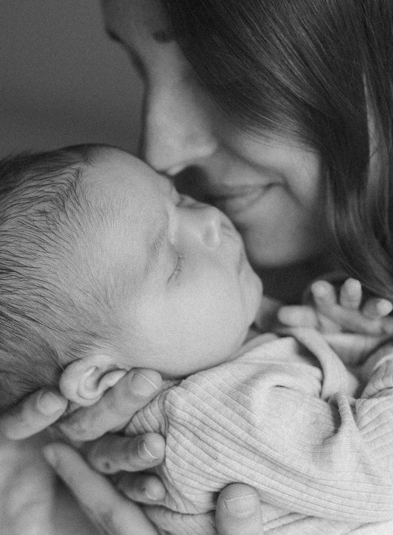Mom kissing newborn baby during in-home lifestyle session