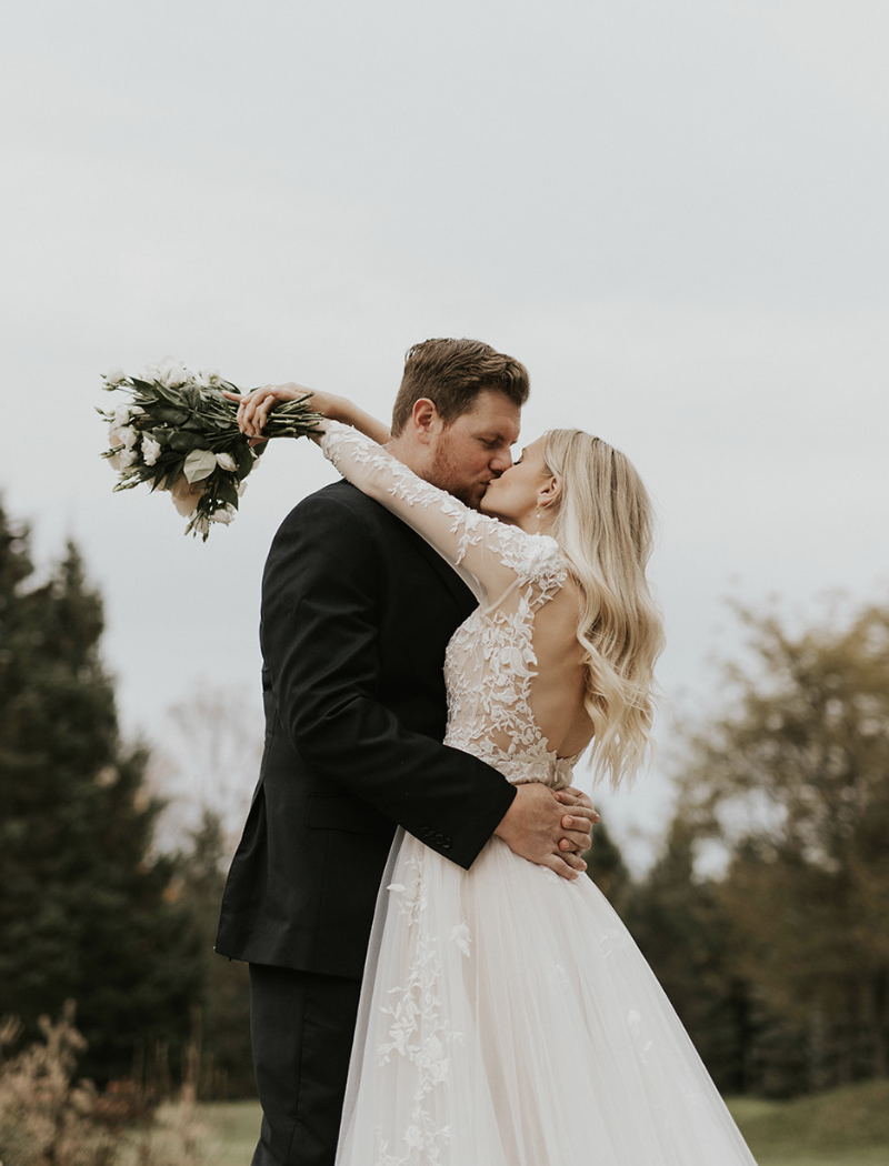 Bride and groom kissing outdoors at Erin Estate during romantic wedding portrait